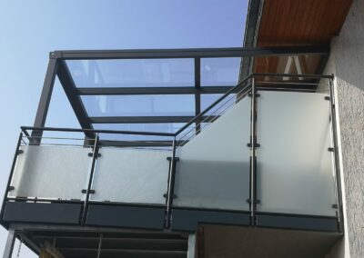 Balkonüberdachung mit einem Glasdach und einem Glas-Aluminiumgeländer aus Milchglas