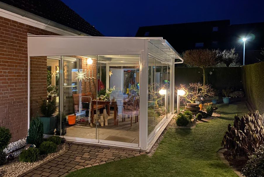 Aufnahme bei Nacht eines Sommergratens aus weißen Aluminiumgestell integriert in einem Garten.